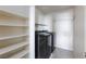Laundry room with black washer and dryer, shelving, and neutral walls at 5204 Sunstone Mesa Dr, Las Vegas, NV 89166