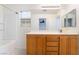 Well-lit bathroom with oak vanity, large mirror, and shower-tub combo at 689 Lucky Pine St, Henderson, NV 89002