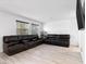 Open living room featuring tile flooring, a dark leather sofa set, and large windows at 715 Pickled Pepper Pl, Henderson, NV 89011