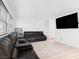 Spacious living room featuring tile flooring, a dark leather sofa set, and a large-screen television at 715 Pickled Pepper Pl, Henderson, NV 89011