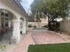 Landscaped backyard featuring a covered patio, artificial grass, pavers, and mature trees at 8396 Yamhill St, Las Vegas, NV 89123