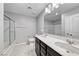 Bright bathroom featuring double vanity, white countertops, and a glass-enclosed shower over the bathtub at 8502 Torozo Ave, Las Vegas, NV 89149