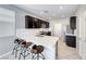 Modern kitchen with dark cabinetry, stainless steel appliances, quartz countertops, and three stools at 8502 Torozo Ave, Las Vegas, NV 89149