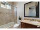 Bright bathroom with a shower over tub, featuring neutral tile and a framed mirror over the sink at 10 Greely Club Trl, Henderson, NV 89052