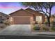 Charming single story home featuring a two car garage, desert landscaping and beautiful sunset sky at 1009 Fishing St, Henderson, NV 89011