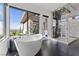 Primary bath features a soaking tub, picture window, and glass enclosed shower with striking stone accents at 11 Cloud Chaser Blvd, Henderson, NV 89012