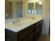 Bright bathroom featuring a double sink vanity with white countertop and dark wood cabinets and two decorative mirrors at 11489 Belmont Lake Dr # 106, Las Vegas, NV 89135
