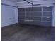 View of an empty attached single car garage with a gray door and concrete floors in neutral tones at 11489 Belmont Lake Dr # 106, Las Vegas, NV 89135