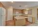 Well-lit kitchen with wood cabinets, an island, and a view of the carpeted dining/living room at 12045 Yarrow Ridge Ct, Las Vegas, NV 89183