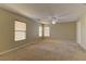 Expansive living room with neutral carpet, ceiling fan, and natural light, ready for personalized decor at 12045 Yarrow Ridge Ct, Las Vegas, NV 89183