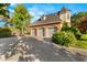 View of the brick three-car garage with an upper story and paved driveway and mature trees at 3001 Astoria Pines Cir, Las Vegas, NV 89107