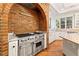 Chef's kitchen with stainless steel oven and hood, brick detailing, and granite countertops at 3001 Astoria Pines Cir, Las Vegas, NV 89107