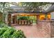 Covered outdoor dining space with a large table, brick columns, and views of the manicured backyard at 3001 Astoria Pines Cir, Las Vegas, NV 89107