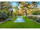 Backyard with a long swimming pool surrounded by artificial turf, landscaping and greenery at 3001 Astoria Pines Cir, Las Vegas, NV 89107