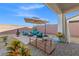 Charming backyard with an umbrella-covered seating area, small wooden bridge, and manicured landscaping at 4050 Peaceful Dune St, Las Vegas, NV 89129