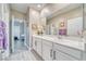 Bathroom with double sinks, white cabinetry, a large mirror, and gray wood-look floors at 4680 Peppertree St, Pahrump, NV 89061