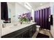 Bathroom with wood-look tile flooring, double sinks, and an elegant purple shower curtain at 6225 Gambetta St, Las Vegas, NV 89115