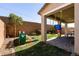 Landscaped backyard featuring a playground, mature trees, and a covered patio at 6308 Gulf Waters St, North Las Vegas, NV 89081