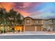 Two-story stucco home with arched entryway, two-car garage, and desert landscaping under a colorful dusk sky at 7479 Lassen Peak Cir, Las Vegas, NV 89149