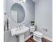 Charming powder room with a pedestal sink, decorative mirror, and modern fixtures at 7479 Lassen Peak Cir, Las Vegas, NV 89149