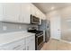 Well-lit kitchen features white cabinets, stainless steel appliances, and tile flooring for easy maintenance at 9130 Haddington Ln, Las Vegas, NV 89145