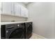 Laundry room with front-loading washer and dryer beneath upper cabinets at 9130 Haddington Ln, Las Vegas, NV 89145