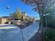 View of the community entrance featuring a walkway, landscaping, wrought iron fence, and neighborhood homes beyond at 10173 Skye Saddle Ave, Las Vegas, NV 89166