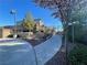 Paved walkway leading to a gated entrance with landscaping, greenery, and blooming tree at 10173 Skye Saddle Ave, Las Vegas, NV 89166