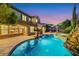 Stunning backyard with a large pool, waterfall feature, and lush landscaping against a twilight sky at 2908 Ferrand Ct, Henderson, NV 89044