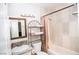 Bathroom with light tile, shower and tub combination, marble countertop sink and metal storage at 301 Falcon Ln, Las Vegas, NV 89107