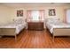 Bright bedroom featuring two beds with floral comforters, hardwood floors and a wooden dresser at 301 Falcon Ln, Las Vegas, NV 89107