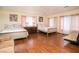 Spacious bedroom with hardwood floors, two beds with floral linens, dresser, and pink curtains at 301 Falcon Ln, Las Vegas, NV 89107