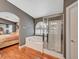 Bright bathroom featuring a soaking tub with arch window, glass enclosed shower, and hardwood flooring adjoining a bedroom at 3723 Robin Knot Ct, North Las Vegas, NV 89084