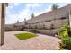 Large backyard with a brick patio, patch of grass, and a tiered retaining wall with lush landscaping at 397 American Dipper St, Las Vegas, NV 89138