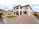 A spacious backyard with a brick patio, patch of grass, and a two-story home with a balcony at 397 American Dipper St, Las Vegas, NV 89138