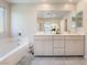 Bathroom with a soaking tub, bright cabinets, dual sinks, and a decorative floral centerpiece at 397 American Dipper St, Las Vegas, NV 89138