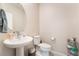 Cozy powder room with a pedestal sink, round mirror, and toilet, accented with decorative items at 397 American Dipper St, Las Vegas, NV 89138