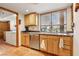 Kitchen with a stainless steel dishwasher, sink, and wood cabinetry next to the laundry area at 519 N Racetrack Rd, Henderson, NV 89015