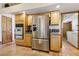 Kitchen with stainless steel refrigerator, oven, and ample wooden cabinetry, adjacent to the laundry area at 519 N Racetrack Rd, Henderson, NV 89015