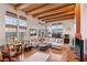 Bright living room with wood floors, exposed wood beam ceiling, a large L-shaped couch, and many windows at 519 N Racetrack Rd, Henderson, NV 89015