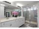 Bright bathroom featuring a double vanity with white cabinets, granite counters, and a glass-enclosed shower at 6346 Rock Strm Ln, Las Vegas, NV 89141