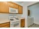 Functional kitchen featuring modern white appliances and wooden cabinetry at 7163 S Durango Dr # 302, Las Vegas, NV 89113