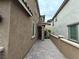 A side view of the house with an alley, showcasing the textured exterior and pathway at 8105 Switchback Run St, Las Vegas, NV 89166