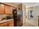 Traditional kitchen with wooden cabinets, black refrigerator, and tile flooring at 8324 W Charleston Blvd # 2053, Las Vegas, NV 89117