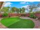 A beautiful backyard with turf grass, manicured shrubs, and brick walls at 10223 Aragon Crown Rd, Las Vegas, NV 89135