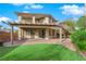 Beautiful backyard featuring a covered patio, artificial grass, and a well-maintained garden with lush greenery at 10223 Aragon Crown Rd, Las Vegas, NV 89135