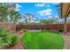 Charming backyard featuring a brick wall, lush green turf, and a stone firepit area for outdoor gatherings at 10223 Aragon Crown Rd, Las Vegas, NV 89135