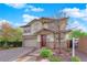 Charming two-story home featuring stone accents, a well-manicured yard, and a welcoming red front door at 10223 Aragon Crown Rd, Las Vegas, NV 89135