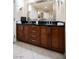 Bathroom vanity featuring double sinks, dark countertops, wood cabinets, and a large mirror at 125 E Harmon Ave # 3406 & 3408, Las Vegas, NV 89109
