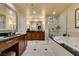 Bright bathroom featuring dual vanities with dark countertops, a soaking tub, and a glass-enclosed shower at 125 E Harmon Ave # 3406 & 3408, Las Vegas, NV 89109
